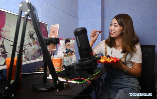 Στην φωτογραφία μια παρουσιάστρια ζωντανής μετάδοσης κάνει μια εκπομπή τοπικών προϊόντων σε μια εταιρεία επικοινωνίας στην κομητεία Ντανφένγκ, Σανγκλουό, στην επαρχία Σαανσί της βορειοδυτικής Κίνας, στις 20 Ιουλίου 2020.(Xinhua / Liu Xiao)