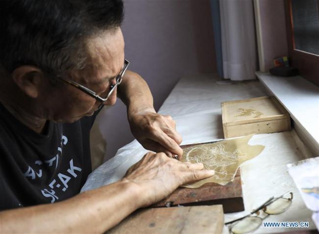 Ο καλλιτέχνης του θεάτρου σκιών Τσάι Σαντσούν, φτιάχνει μια φιγούρα στο σπίτι του στο χωριό Ντουτσούν της κομητείας Γιανγκσιάν, που βρίσκεται στην επαρχία Σαανσί της βορειοδυτικής Κίνας, 1η Αυγούστου 2020. (φωτογραφία/Xinhua)