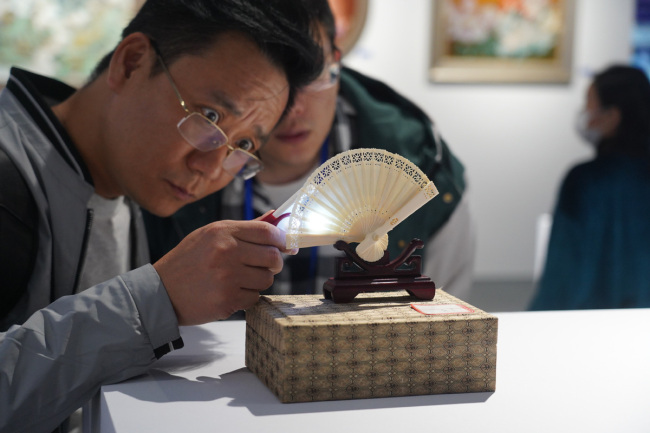 Επισκέπτες παρατηρούν πορσελάνινα αντικείμενα κατά τη διάρκεια της Διεθνούς Έκθεσης Κεραμικής στο Τζινγκντετζέν, επαρχία Τζιανγκσί, 18 Οκτωβρίου 2020. [Φωτογραφία / Xinhua]