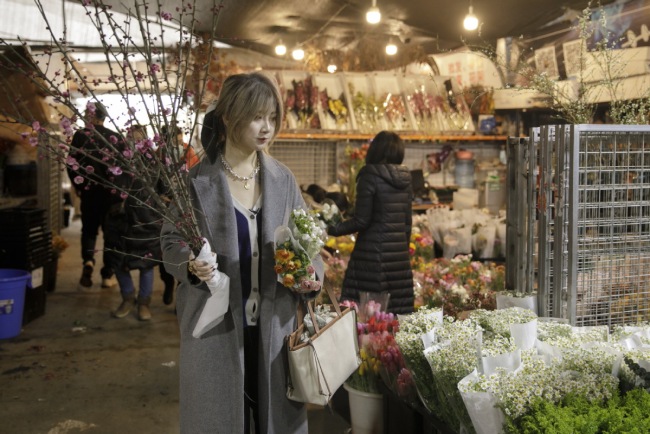 Η Ζενγκ Σι επιλέγει λουλούδια σε μια αγορά στο Τσενγκντού, στην επαρχία Σιτσουάν της Νοτιοδυτικής Κίνας, στις 28 Ιανουαρίου 2021. [Xinhua]