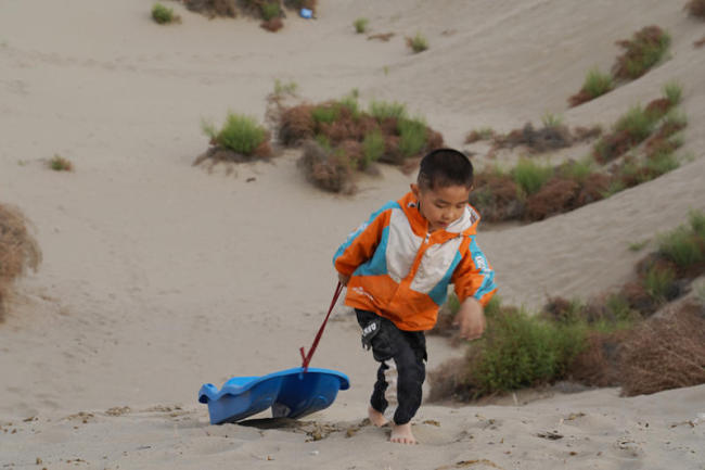 8. Ένα παιδάκι παίζει στην άκρη της Τακλαμακάν στην πόλη Χοτάν, στην αυτόνομη περιοχή Σιντζιάνγκ Ουιγκούρ της βορειοδυτικής Κίνας, 22 Μαΐου 2021.