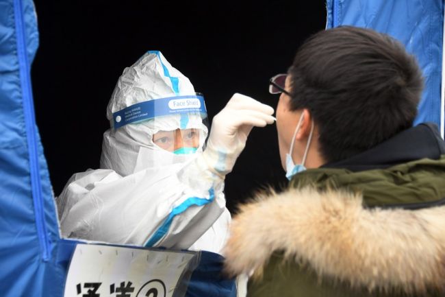 Një punonjës mjekësor mori një mostër tamponi nga një banorë në një pikë të testimit të COVID-19 në distriktin Haidian të Pekinit, më 24 janar 2022/ Xinhua
