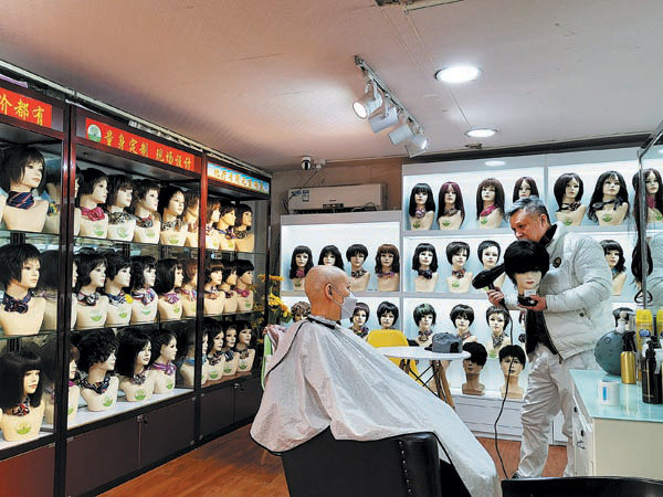 Wang Feng (djathtas), pronar i sallonit të flokëve Shuting, bën një parukë për një pacient me kancer, në mars 2021.Foto nga Xinhua