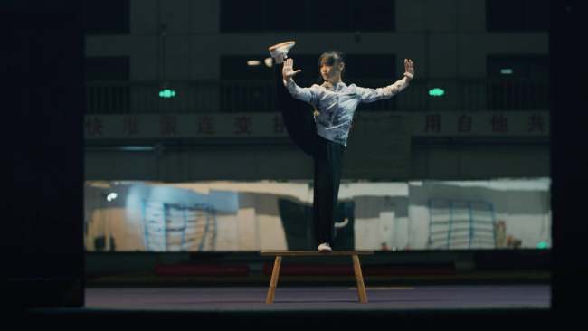 Liang Biying ushtron pozicionet e këmbëve në një tra ekuilibri. /CGTN