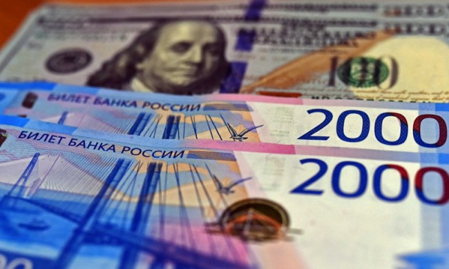 Bankovky ruských rublů vyobrazené s US dolary na pozadí, 2. března. 2021.(Photo: Xinhua)
