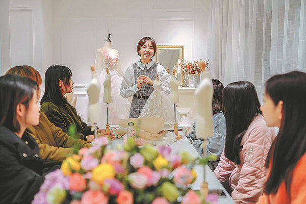 Η σχεδιάστρια μόδας Τσάο Γιουτίνγκ (στο κέντρο) μιλά με υπαλλήλους στο στούντιό της στην πόλη Τσεντζόου, στην επαρχία Χουνάν. Η Τσάο Γιουτίνγκ λαβαίνει τεράστια υποστήριξη από τους ακολούθους της στο διαδίκτυο για τα μίνι νυφικά της. [China Daily]