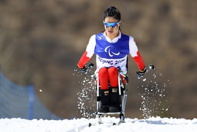 Η Γιανγκ Χονγκτσιόνγκ της Κινεζικής Ομάδας ενώ διαγωνίζεται στο αγώνισμα μεσαίων αποστάσεων στο καθιστό σκι αντοχής γυναικών στους Χειμερινούς Παραολυμπιακούς Αγώνες 2022 στο Εθνικό Κέντρο Διάθλον στο Τζανγκτζιακόου, στην επαρχία Χεμπέι της βόρειας Κίνας, 12 Μαρτίου 2022. /CFP