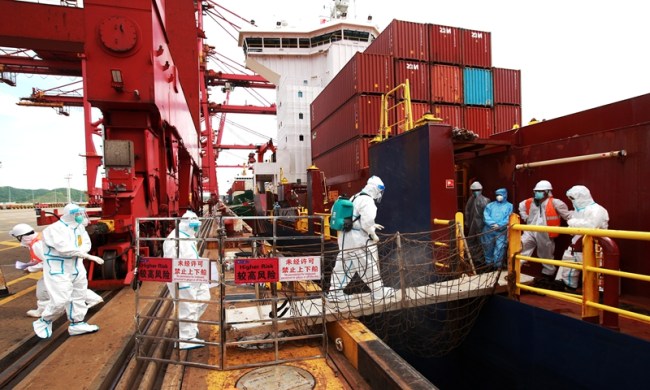V Singapuru registrovaná kontejnerová loď „Asiatic Nepture“ kotví v Zhoushanu ve východočínské provincii Zhejiang, 10. července 2021. Celníci se okamžitě na plavidlo nalodili, aby provedli zdravotní inspekci. Photo: VCG