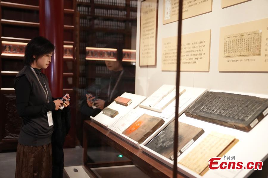 Επισκέπτρια παρατηρεί κειμήλια εκτύπωσης που εκτίθενται στο Μουσείο του Παλατιού στο Πεκίνο, στις 30 Οκτωβρίου 2023. (Φωτογραφία: China News Service/Shi Chunyang)