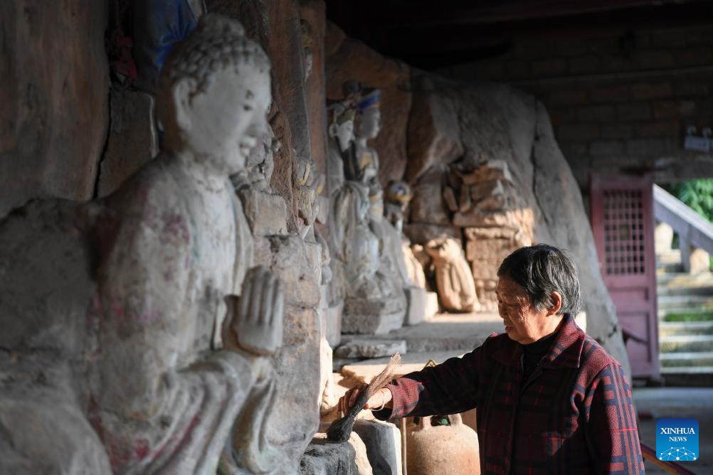 Ένας εθελοντής καθαρίζει ένα άγαλμα σε ένα χώρο προστασίας πολιτιστικών κειμηλίων των Βράχων Νταζού στο Τζονγκάο του Νταζού στο Τσονγκτσίνγκ της νοτιοδυτικής Κίνας στις 31 Οκτωβρίου 2023.