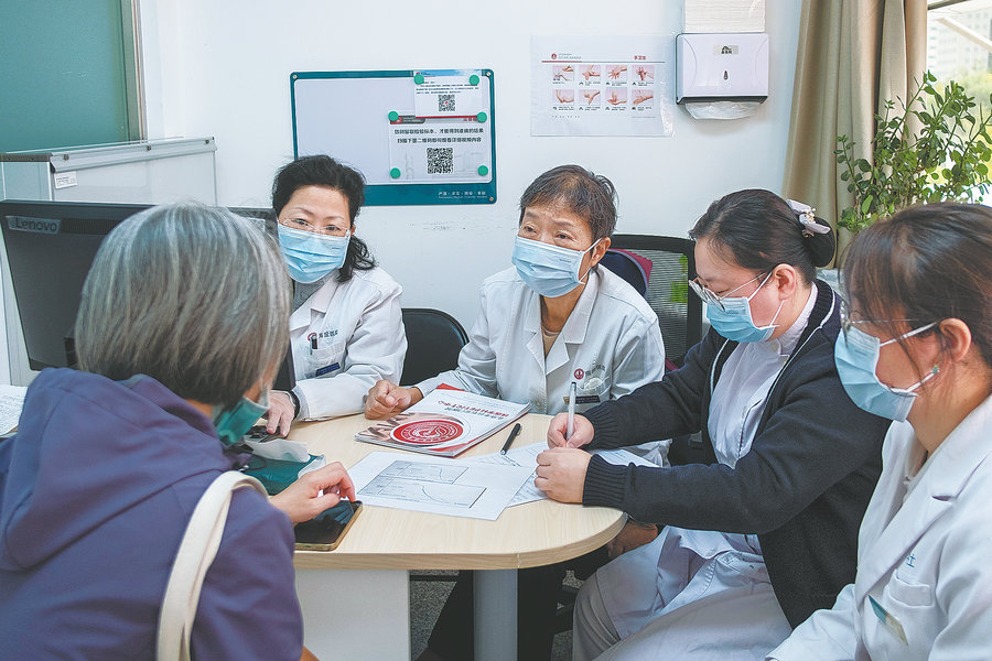 Η Τσιν Γιουάν (στη μέση), επικεφαλής του κέντρου παρηγορητικής φροντίδας του Νοσοκομείου Haidian του Πεκίνου, μιλάει με έναν ασθενή. [Φωτογραφία από Pan Songgang/Sun Ren/For China Daily]