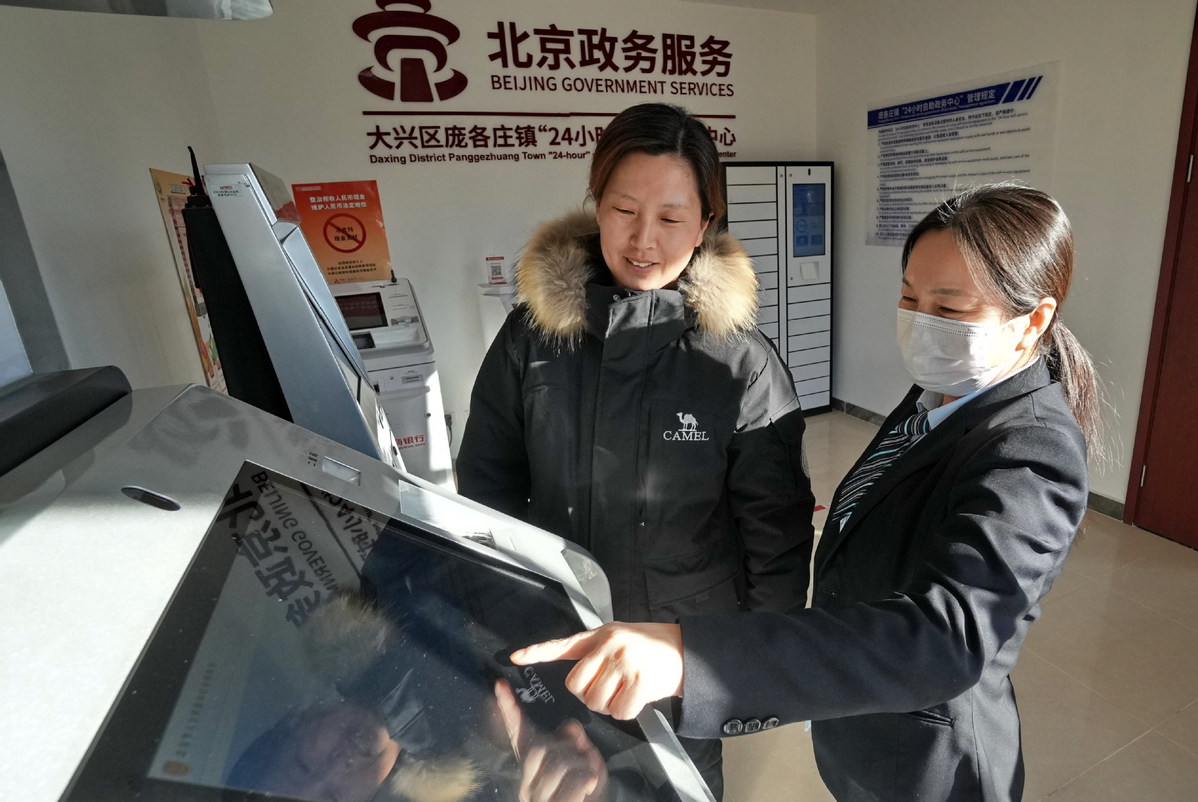Μια υπάλληλος (δεξιά) δείχνει σε μια γυναίκα πώς να ελέγξει τον λογαριασμό της κοινωνικής ασφάλισης σε ένα κέντρο υπηρεσιών της πόλης στην περιοχή Ντασίνγκ του Πεκίνου, στις 22 Ιανουαρίου. [Φωτογραφία/Xinhua]