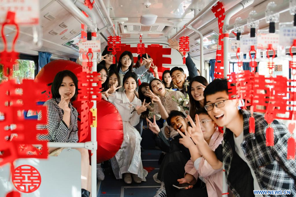 Φωτογραφία από τις 28 Οκτωβρίου 2023 των νεόνυμφων Τανγκ Σαντσίνγκ και Χου Τσιενκούν που ποζάρουν για φωτογραφία με τους συγγενείς και τους φίλους τους σε ένα γαμήλιο λεωφορείο, στο Σουτσιέν, στην επαρχία Τζιανγκσού της ανατολικής Κίνας. (Xinhua)