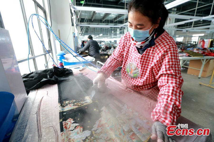 Εργάτριες σιδερώνουν τις ‘φούστες προσώπου αλόγων’ σε ένα εργοστάσιο ένδυσης στην κομητεία Τσαοσιέν, στην επαρχία Σανντόνγκ της ανατολικής Κίνας, 4 Μαρτίου 2024. (Φωτογραφία: China News Service/Liang Ben)